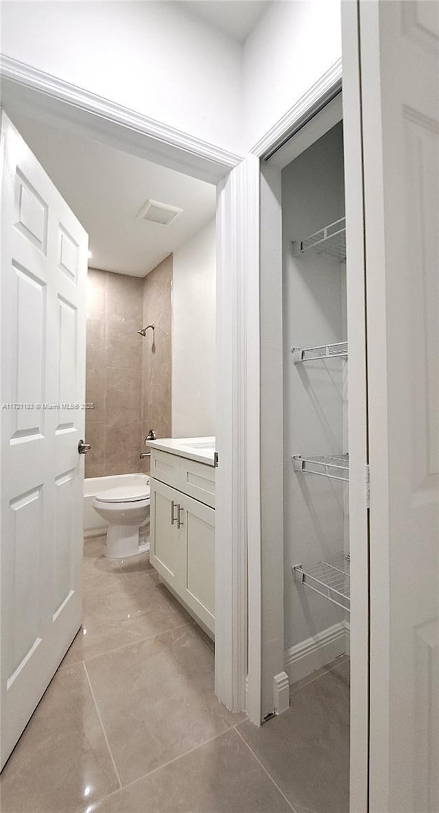 full bathroom with tile patterned floors, tiled shower / bath, vanity, and toilet