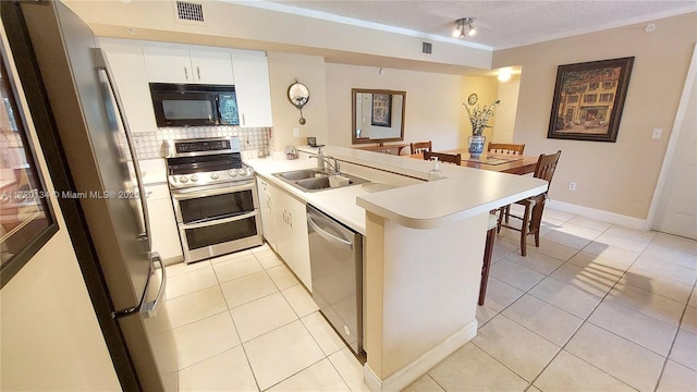 kitchen with white cabinetry, sink, kitchen peninsula, light tile patterned floors, and appliances with stainless steel finishes