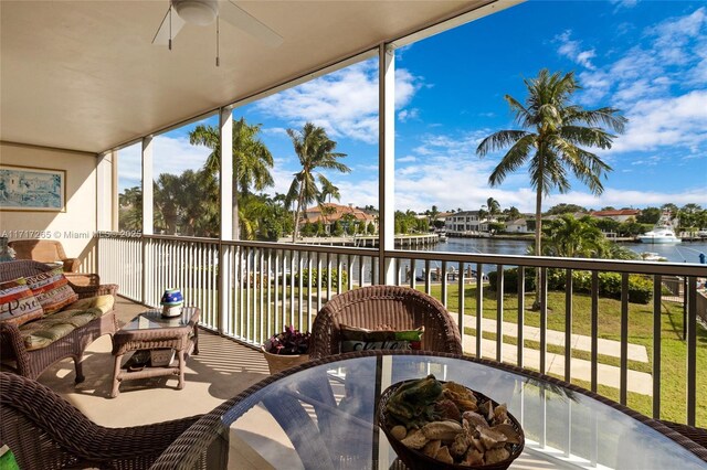 sunroom / solarium featuring ceiling fan and a water view