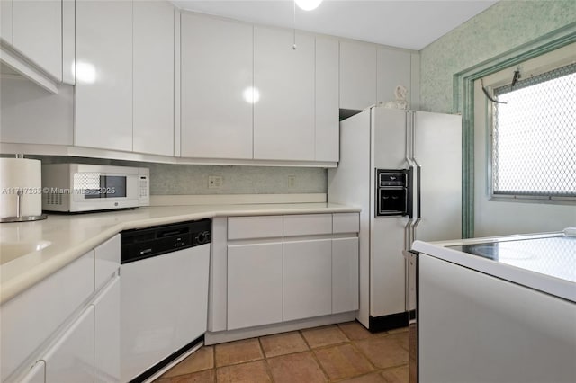 kitchen featuring white cabinetry, light tile patterned floors, and white appliances