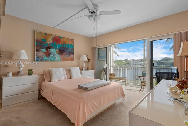 bedroom with access to exterior, light colored carpet, ceiling fan, and a water view