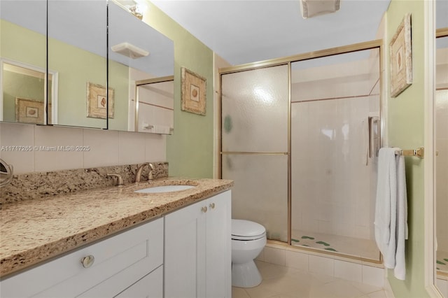 bathroom featuring toilet, vanity, tasteful backsplash, and a stall shower