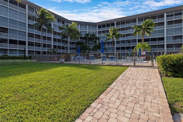 view of community featuring fence and a yard
