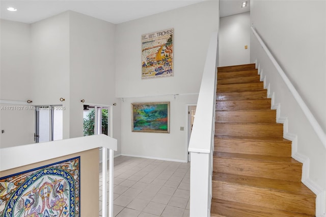 stairs with tile patterned flooring and a high ceiling