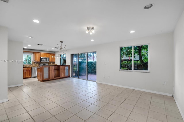 kitchen with light tile patterned flooring, a chandelier, hanging light fixtures, stainless steel appliances, and backsplash