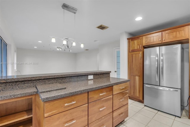 kitchen with light tile patterned floors, stainless steel fridge, and dark stone counters