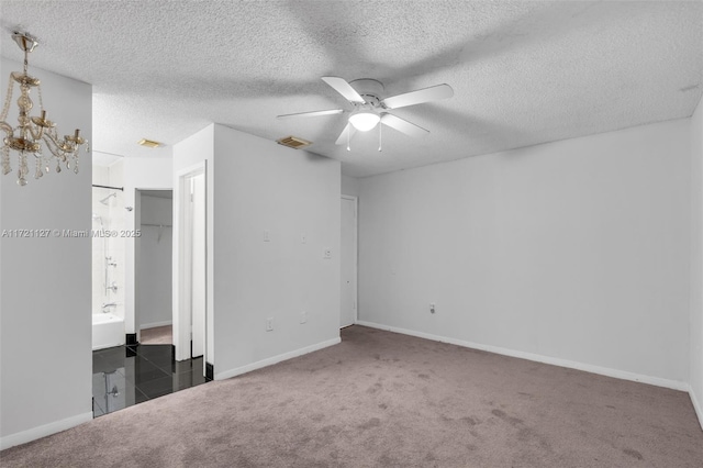 unfurnished bedroom with ceiling fan with notable chandelier, a textured ceiling, and dark colored carpet