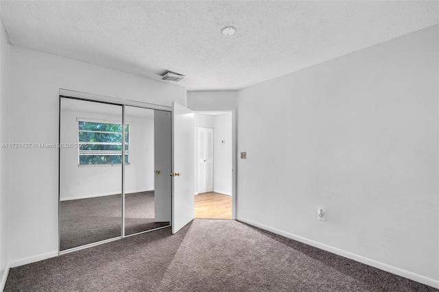 unfurnished bedroom featuring a closet, a textured ceiling, and carpet