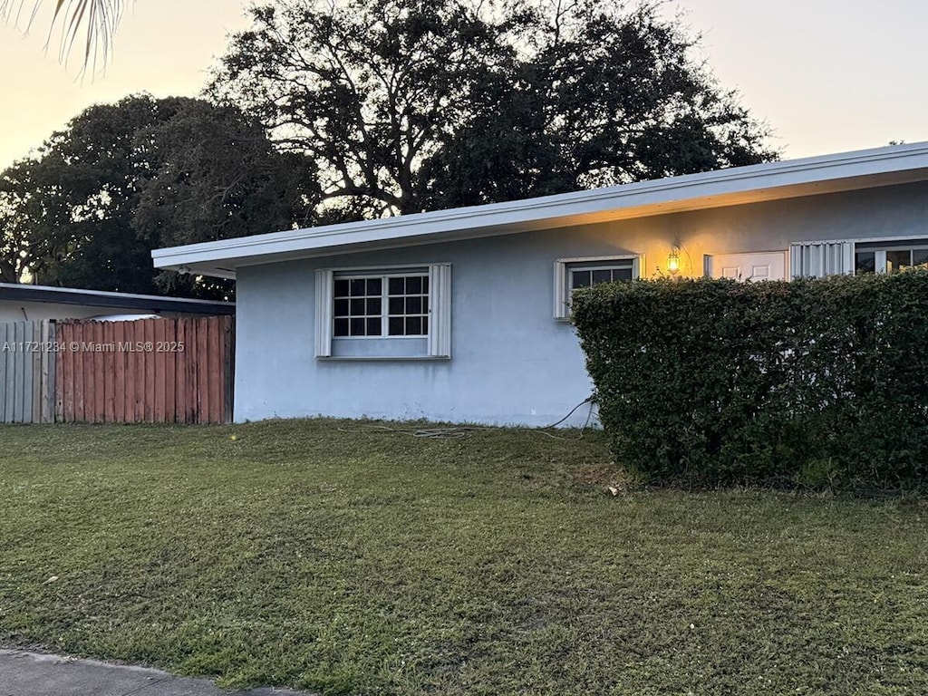 property exterior at dusk featuring a yard