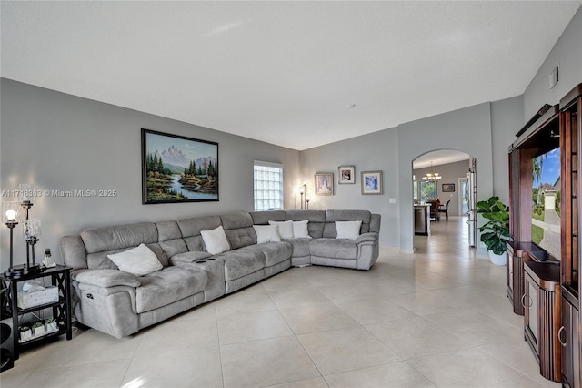 living room with light tile patterned floors, vaulted ceiling, and a notable chandelier