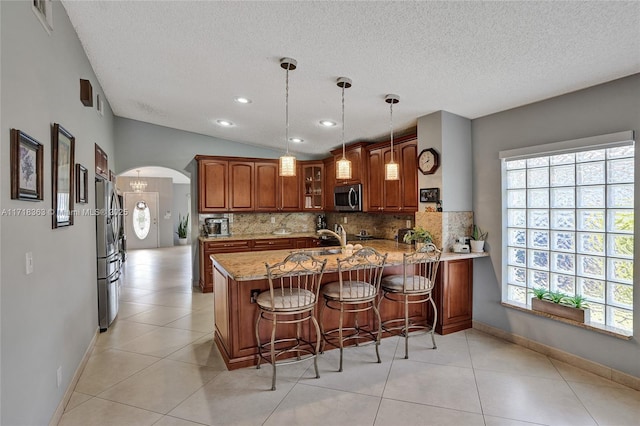 kitchen with hanging light fixtures, stainless steel appliances, tasteful backsplash, kitchen peninsula, and lofted ceiling