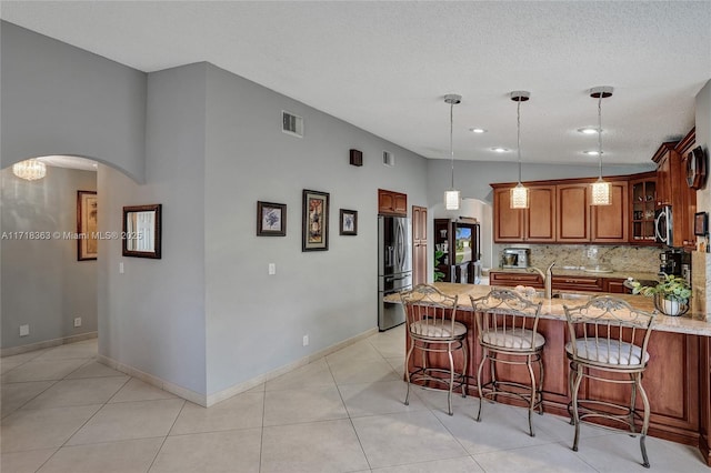 kitchen with a kitchen breakfast bar, tasteful backsplash, stainless steel appliances, vaulted ceiling, and pendant lighting