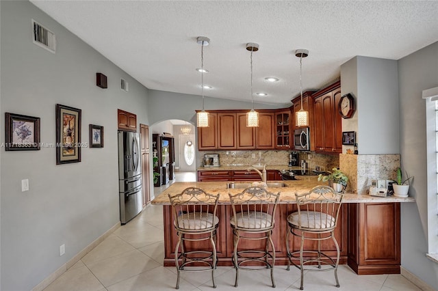 kitchen featuring sink, stainless steel appliances, kitchen peninsula, decorative light fixtures, and decorative backsplash