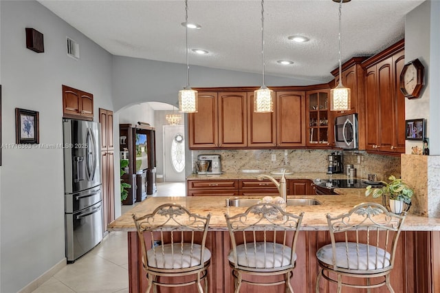 kitchen with a textured ceiling, stainless steel appliances, sink, pendant lighting, and lofted ceiling