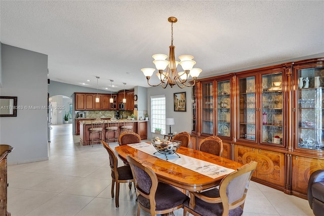 dining space featuring a chandelier, light tile patterned floors, a textured ceiling, and lofted ceiling