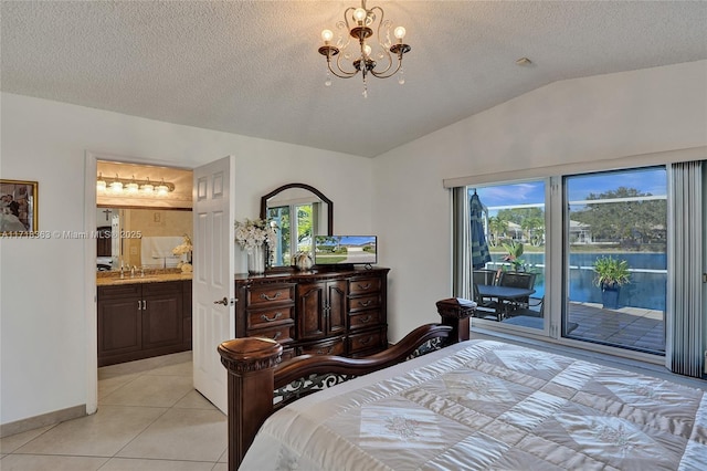 bedroom featuring ensuite bath, a textured ceiling, lofted ceiling, access to outside, and light tile patterned floors