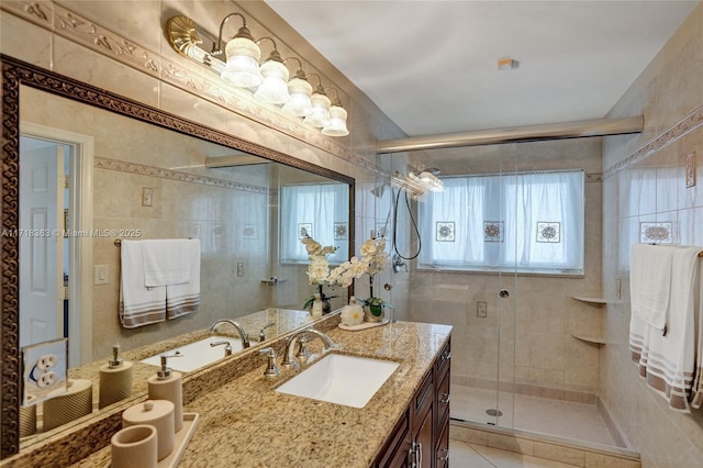 bathroom featuring tile patterned flooring, vanity, a shower with door, and tile walls