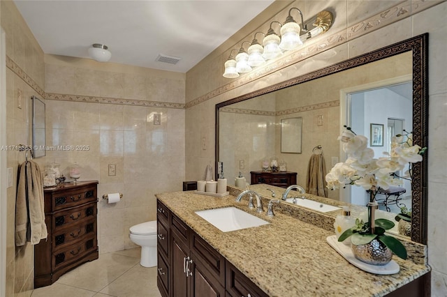 bathroom with tile patterned floors, vanity, tile walls, and toilet