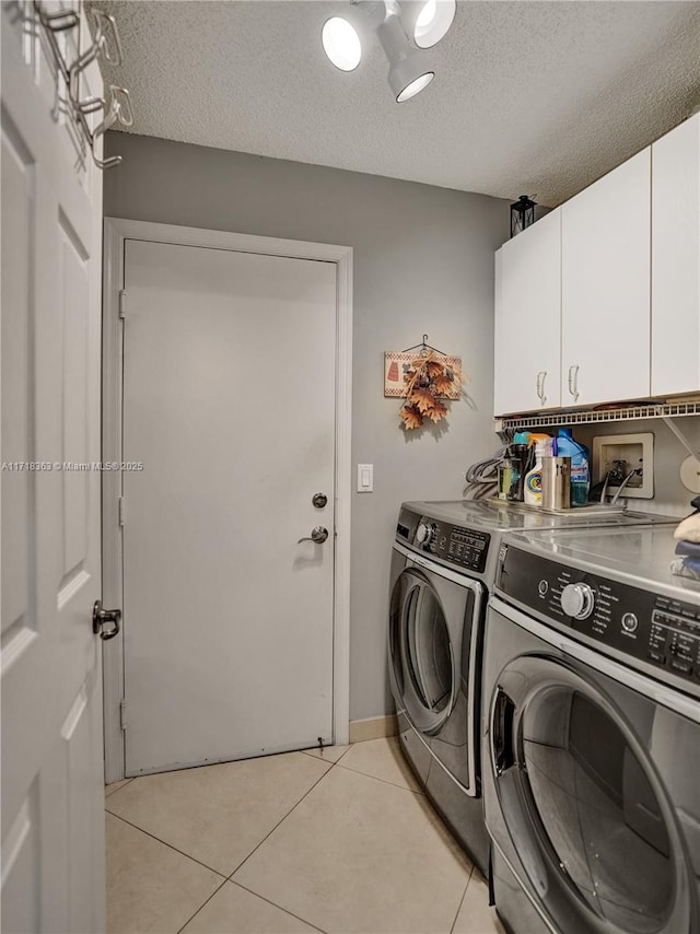 laundry room featuring washer and dryer, light tile patterned floors, a textured ceiling, and cabinets