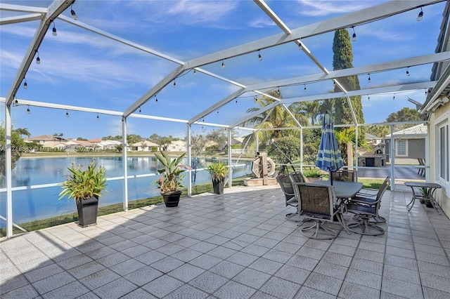 view of patio with a lanai and a water view