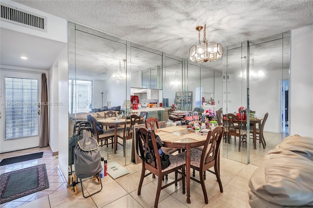 tiled dining area with a textured ceiling and an inviting chandelier