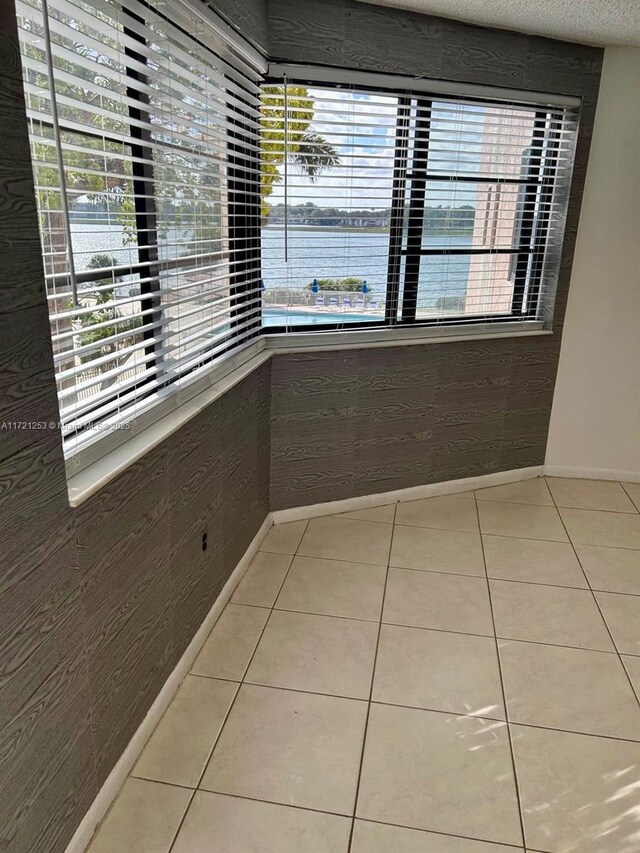 interior space featuring a water view, a textured ceiling, and light tile patterned flooring