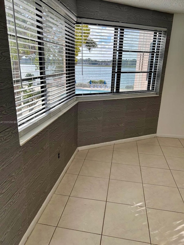 interior space featuring light tile patterned flooring, a textured ceiling, and baseboards