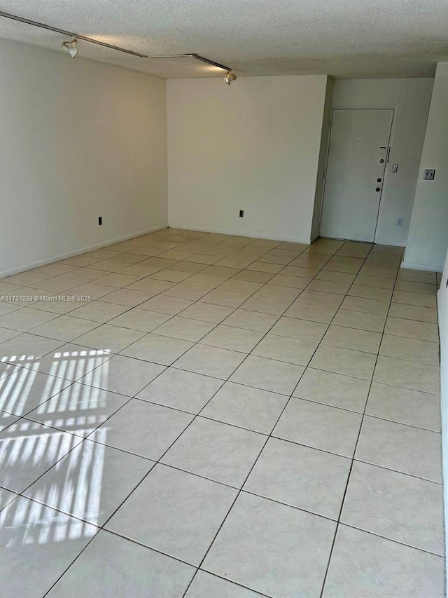 unfurnished room with a textured ceiling and light tile patterned flooring