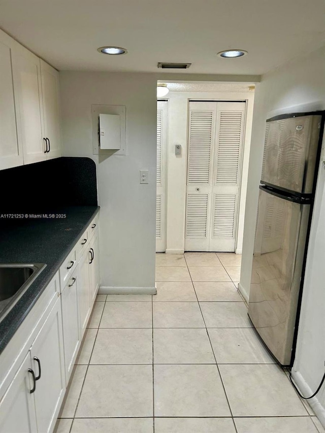 kitchen with light tile patterned floors, white cabinets, and freestanding refrigerator