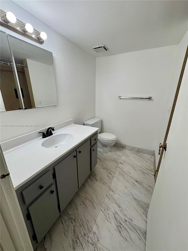 bathroom featuring visible vents, toilet, vanity, marble finish floor, and a textured ceiling