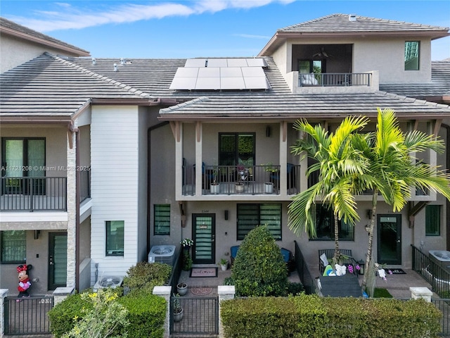 multi unit property featuring a tile roof, solar panels, and stucco siding