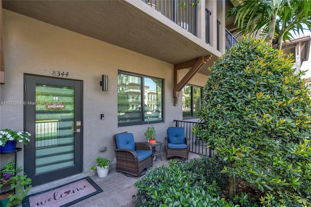 property entrance with a balcony and stucco siding