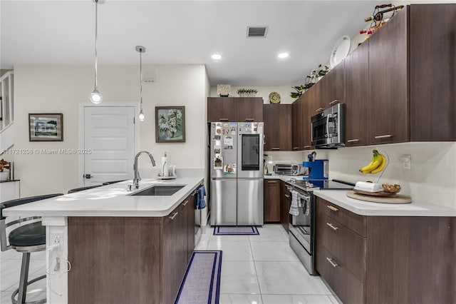 kitchen with hanging light fixtures, stainless steel appliances, dark brown cabinets, light countertops, and a sink