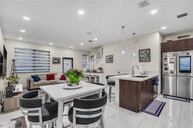 kitchen featuring a sink, visible vents, light countertops, dark brown cabinets, and hanging light fixtures