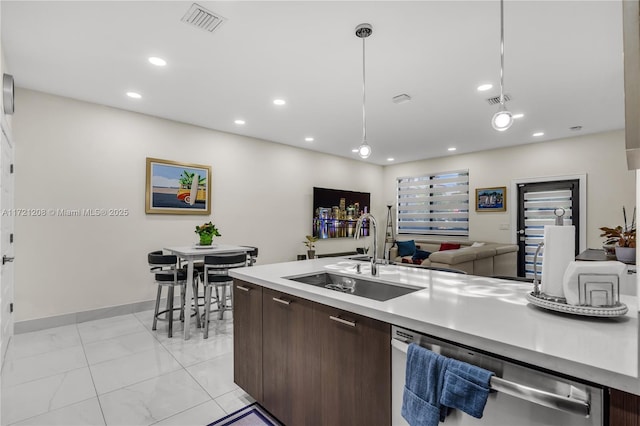 kitchen featuring dark brown cabinetry, a sink, light countertops, dishwasher, and pendant lighting