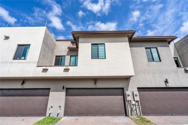 townhome / multi-family property with a garage and stucco siding