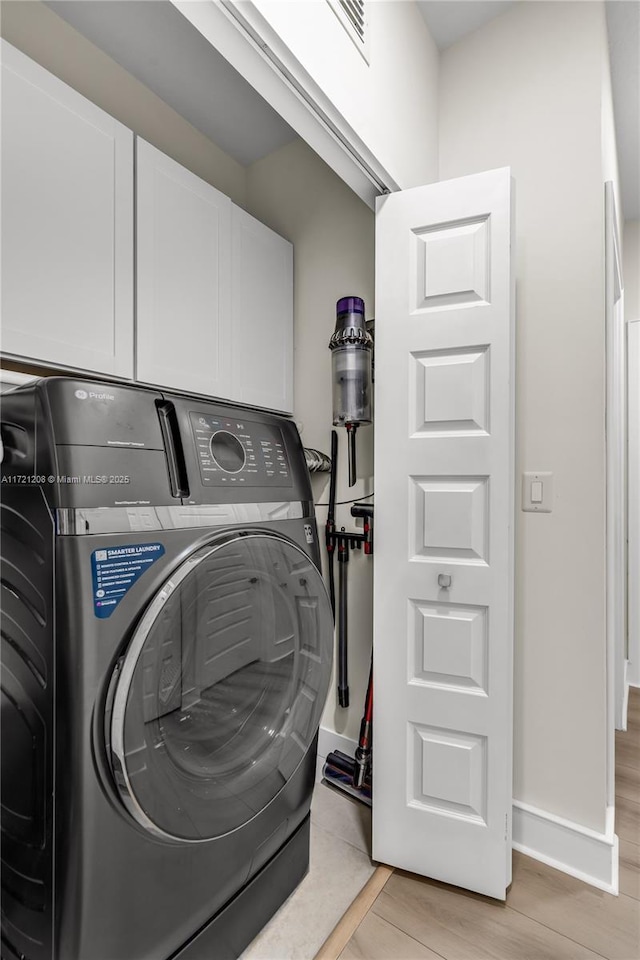 laundry room with cabinet space, visible vents, baseboards, and light wood finished floors