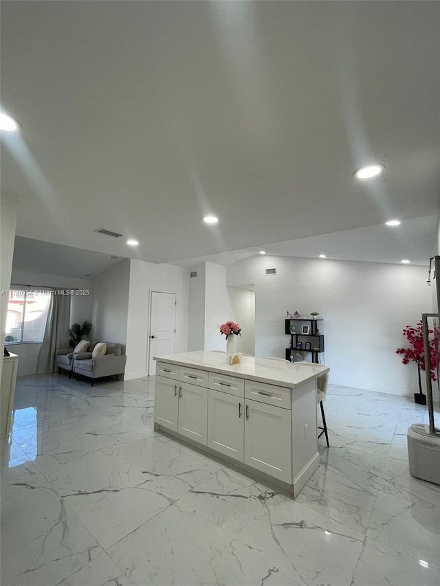 kitchen featuring white cabinets, a kitchen island, and a breakfast bar area