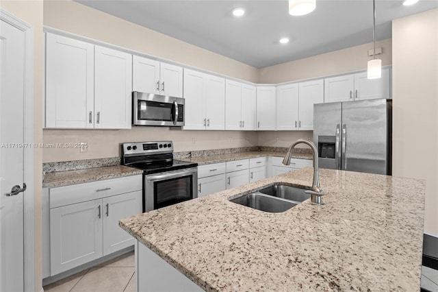 kitchen featuring white cabinetry, sink, hanging light fixtures, stainless steel appliances, and an island with sink