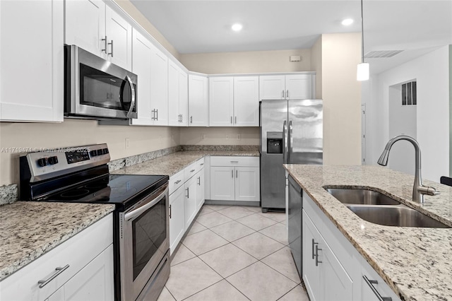 kitchen featuring pendant lighting, white cabinets, sink, light stone countertops, and stainless steel appliances