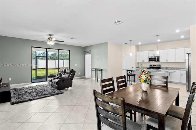 tiled dining space with ceiling fan and sink