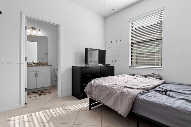 bedroom with ensuite bathroom and light tile patterned flooring