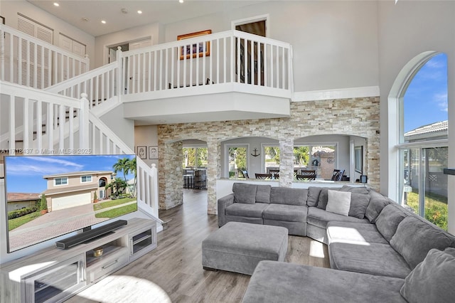 living room with a wealth of natural light, wood-type flooring, and a high ceiling