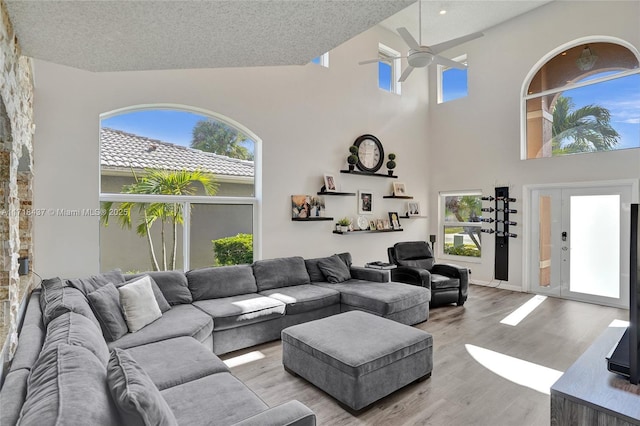 living room with ceiling fan, light hardwood / wood-style floors, lofted ceiling, and a textured ceiling