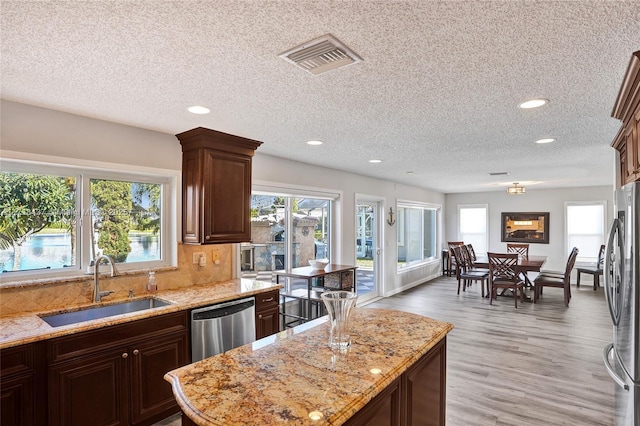 kitchen featuring light stone countertops, a textured ceiling, stainless steel appliances, and sink