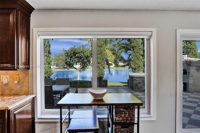 dining room with a healthy amount of sunlight, a water view, and a textured ceiling