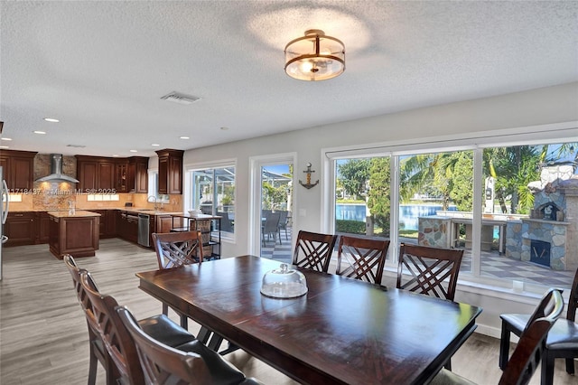 dining space featuring a textured ceiling and light hardwood / wood-style floors