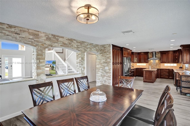 dining room with sink, light hardwood / wood-style floors, and a textured ceiling