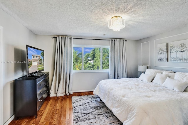 bedroom featuring wood-type flooring, a textured ceiling, and an inviting chandelier