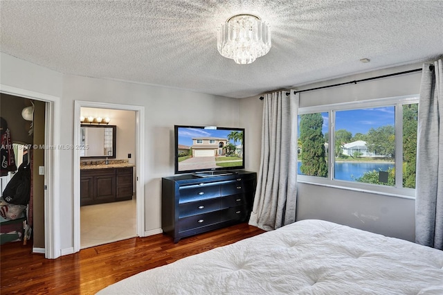 bedroom featuring dark hardwood / wood-style floors, a chandelier, connected bathroom, and multiple windows